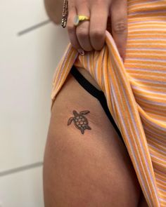 a woman with a small tattoo on her thigh shows off her tiny turtle - shaped stomach