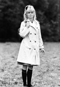 black and white photograph of a woman in a trench coat holding a dog on a leash