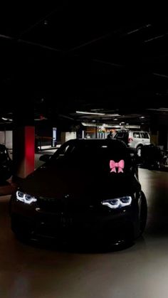 some cars parked in a parking garage with pink bows on the hoods and lights