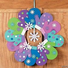 a wreath made out of colorful paper with snowflakes on the front and sides