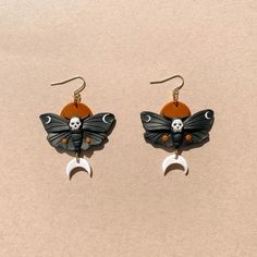 the earrings are decorated with black, orange and white butterflies on crescent moon dangles