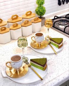 two white plates topped with sandwiches next to cups and saucers on top of a counter