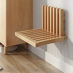 a wooden bed sitting on top of a hard wood floor next to a white wall