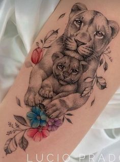 a woman's thigh with a lion and cub tattoo on it