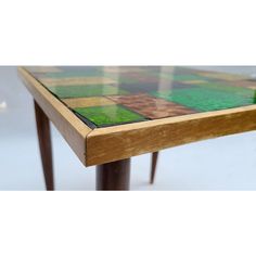 a wooden table with green and yellow tiles on it's top, against a white background