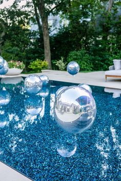 an inflatable ball floating on top of a swimming pool next to lounge chairs