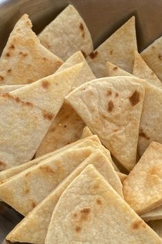 some tortilla chips are in a metal bowl