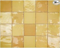 a yellow tiled wall with white and brown tiles