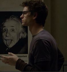 a man standing in front of a poster with an image of himself sticking out his tongue