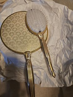 two gold brushes sitting on top of a white sheet