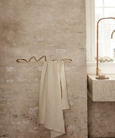 a towel hanging on the wall next to a sink in a room with stone walls