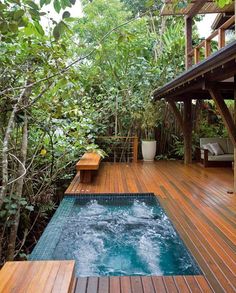 an outdoor hot tub in the middle of a decked area with trees and plants