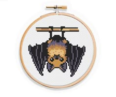 a cross stitch pattern with a bat hanging from it's side