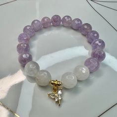 LilacLavender Amethyst & White Quartz Dragonfly Crystal Charm Bracelet. Faceted gemstones in size 10mm. Handmade with durable stretch elastic string.  Size 7.5 inches, approximate. It is believed that the lilac lavender amethyst promotes Inner Peace & Tranquility. Align your Crown Chakra.  CARE INSTRUCTIONS:  Take it off before bathing, exercising, swimming. Keep your bracelet in a dry place.  Don't wear it in a wet environment such as a pool or the ocean.  Avoid perfume, sunscreen, lotions, hai Cheap Lavender Amethyst Jewelry, Luxury Lavender Jewelry For Healing, Cheap Lavender Bracelets For Gifts, Cheap Purple Crystal Bracelet Gift, Cheap Lavender Casual Bracelets, Cheap Lavender Bohemian Bracelet, Luxury Lavender Spiritual Jewelry, Luxury Handmade Lavender Jewelry, Affordable Purple Crystal Bracelet Gift