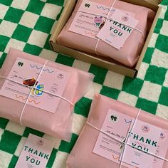 three pink boxes with thank you notes tied to them on a green and white checkered tablecloth