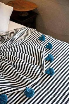 a black and white striped bed spread with blue pom poms