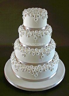 a three tiered wedding cake with white frosting flowers on the top and sides