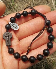 +. This is a Wooden Rosary Bracelet. +.It is knotted bracelet and it is adjustable . +.The crufix is carved in elevorate and three dementional shape. +.+.+.+.+. Materials +.+.+.+.+.+. Cross: Mpingo(Africa black wood) Beads : black wood +.+.+.+.+. Size +.+.+.+.+. Cross : 13.3mm(Width) *20mm(Height) Beads: 8mm +. Carved characters(e.g. baptismal name, name,etc) on back side +. please send me characters that you want. It's Free engraving +.Lead time is 3-7 business days. +.Delivery is currently bei Adjustable Wooden Beads Rosary Bracelet Gift, Adjustable Wooden Bead Rosary Bracelet Gift, Combat Rosary, Bible Jewelry, Rosary Making, Mens Rosary, Wooden Rosary, Cross Wood, Diy Bracelets With String