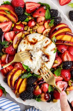 a white plate topped with sliced peaches, strawberries and whipped cream next to a fork