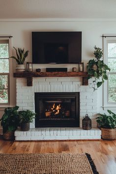 a living room with a fire place and television on the wall, potted plants in front of it