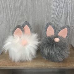 two gray and white stuffed animals on a wooden shelf next to a wood paneled wall