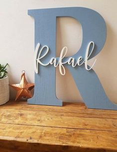 a wooden letter that says raffel on top of a shelf next to a potted plant