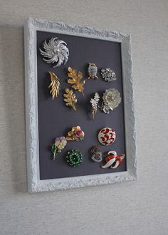 there are many pins in the frame on the wall next to each other, including brooches