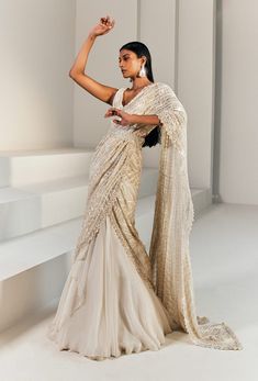 Editor's Note Ivory And Gold Pre-stitched Lehenga Saree Paired With A Fitted Blouse And Belt. Color: Ivory Gold Fabric: Net, Cupro, Organza, Crepe, Double Georgette . Embroidery Details: Bead, Thread, Resham & Bugel. Care: Dry Clean Only About the Designer Ritika Mirchandani is known for its clothes that are wearable and luxurious with a feminine and glamorous feel to them. Luxury Dabka Lehenga With Traditional Drape, Luxury Elegant Saree With Dori Work, Luxury Saree With Dori Work For Reception, Luxury Elegant Net Saree, Luxury Silk Lehenga With Sheer Dupatta, Luxury Lehenga For Puja With Traditional Drape, Luxury Gold Lehenga With Traditional Drape, Luxury Draped Lehenga With Zari Work, Luxury Pre-draped Saree With Sheer Dupatta For Gala