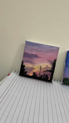 there are two paintings on the shelf next to each other, one is purple and blue