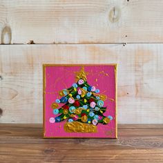 a pink and gold christmas tree painted on wood