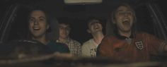 four young men are laughing in the back of a car