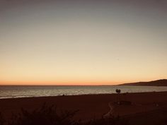 the sun is setting over the ocean and beach