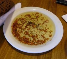 a white bowl filled with soup on top of a wooden table