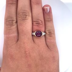 a woman's hand with a ring on it and a purple stone in the middle