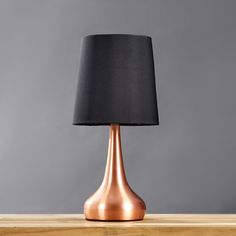 a table lamp with a black shade on it sitting on top of a wooden table