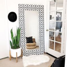 a room with a mirror, plant and rug