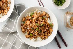 two white bowls filled with rice and meat on top of a table next to chopsticks