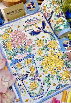 a table topped with lots of different colored markers and paper flowers on top of it