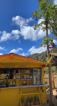 a small yellow shack with pineapples on the outside and blue sky in the background