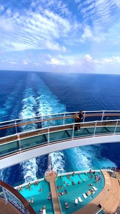 people are on the deck of a cruise ship looking out at the water and swimming pool