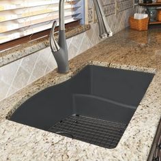 a black sink sitting under a kitchen faucet