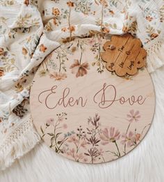 a wooden sign that says eden dove with flowers and leaves around it on a white furnishing