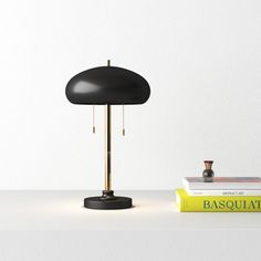 a table lamp sitting on top of a white shelf next to two books and a vase