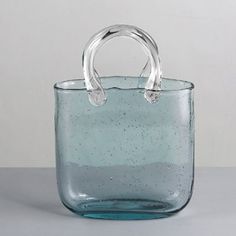 a blue glass bag sitting on top of a white table next to a gray wall