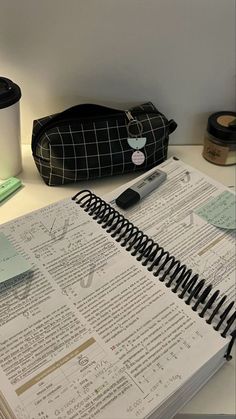 an open notebook sitting on top of a table next to a cup and pen holder