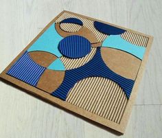 a piece of cardboard with blue and brown shapes on it sitting on a wooden surface