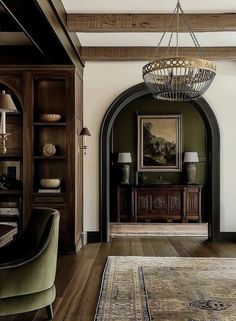 a living room filled with furniture and a chandelier hanging from the ceiling next to a doorway