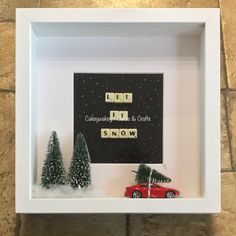 a white frame with a red car and christmas tree in it on top of a stone wall