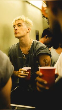 a man with blonde hair holding a red cup