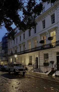 a street with cars parked on the side of it at night in front of a white building